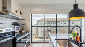 A modern kitchen with a large window, stainless steel appliances, and a black pendant light. - Bachelor Party Pad, 5 Minutes to Broadway + Private Balcony | Last Call (Nashville)