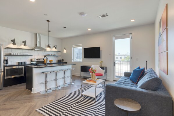 A modern kitchen with a central island, stainless steel appliances, and pendant lighting. - Carter #302 by AvantStay | 1BR + Rooftop Access (Nashville)