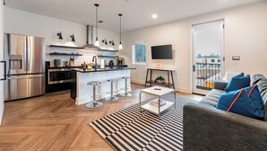 Una cocina moderna con una isla central, electrodomésticos de acero inoxidable e iluminación colgante.