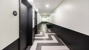 Un pasillo moderno con un diseño de suelo blanco y negro, una puerta con la etiqueta '204' y un accesorio de iluminación en el techo.