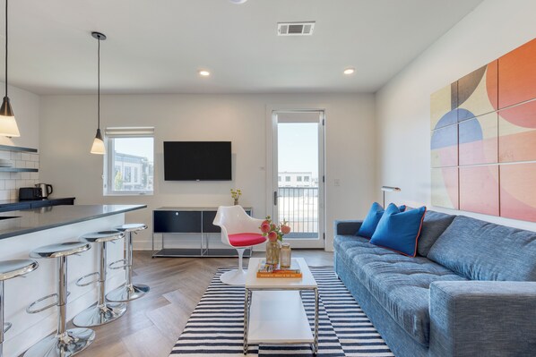 A modern living room with a grey sofa, a coffee table, and a bar area with stools.