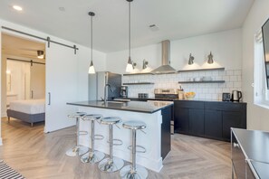 A modern kitchen with a central island, bar stools, stainless steel appliances, and pendant lighting. - Carter #504 by AvantStay | Mins to Downtown (Nashville)