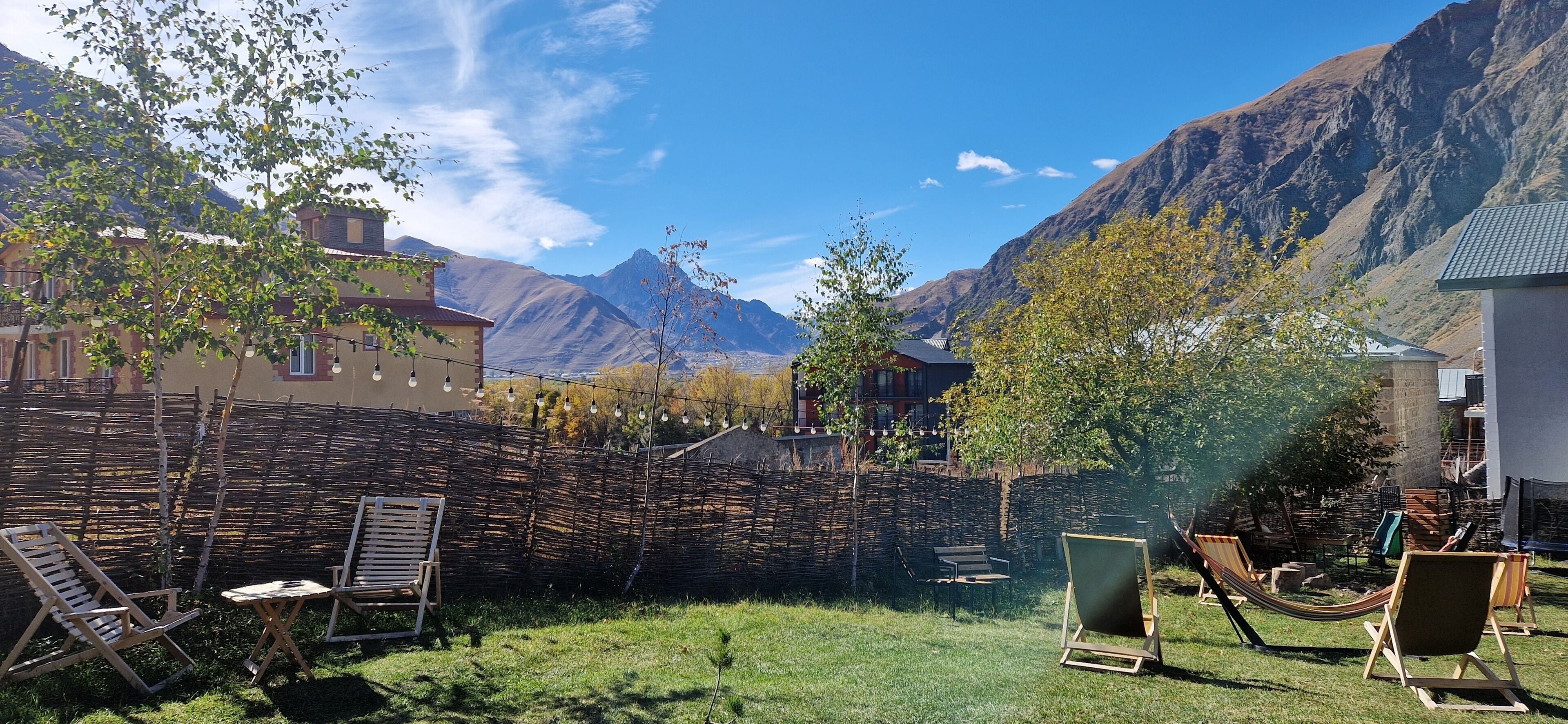 Ein Garten mit einer Hängematte, Liegestühlen und einem Holzzaun.