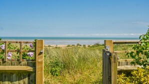 Un portón de madera que da a una playa con vista despejada al océano.