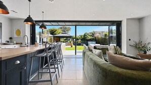 Una cocina moderna con barra, un comedor con asientos exteriores y vistas al jardín.