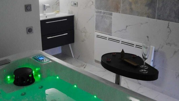 Een moderne badkamer met een groot bad, een zwart badkamermeubel en een spiegel.