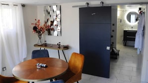 Een moderne kamer met een eettafel, stoelen, een bloemenvaas, een spiegel en een garderobe.
