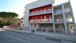 Ein mehrstöckiges Gebäude mit Balkonen und einer roten Fassade.