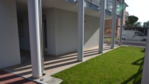 Ein modernes Gebäude mit überdachtem Außenbereich, einem gepflegten Rasen und einem Parkplatz.