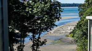 A view of a beach with trees and a body of water. - Ocean Breeze Seaside Studio Condo B (Nanoose Bay)