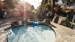 A swimming pool with a tiled floor, a blue slide, and a metal ladder. - Ocean Breeze Seaside Studio Condo B (Nanoose Bay)