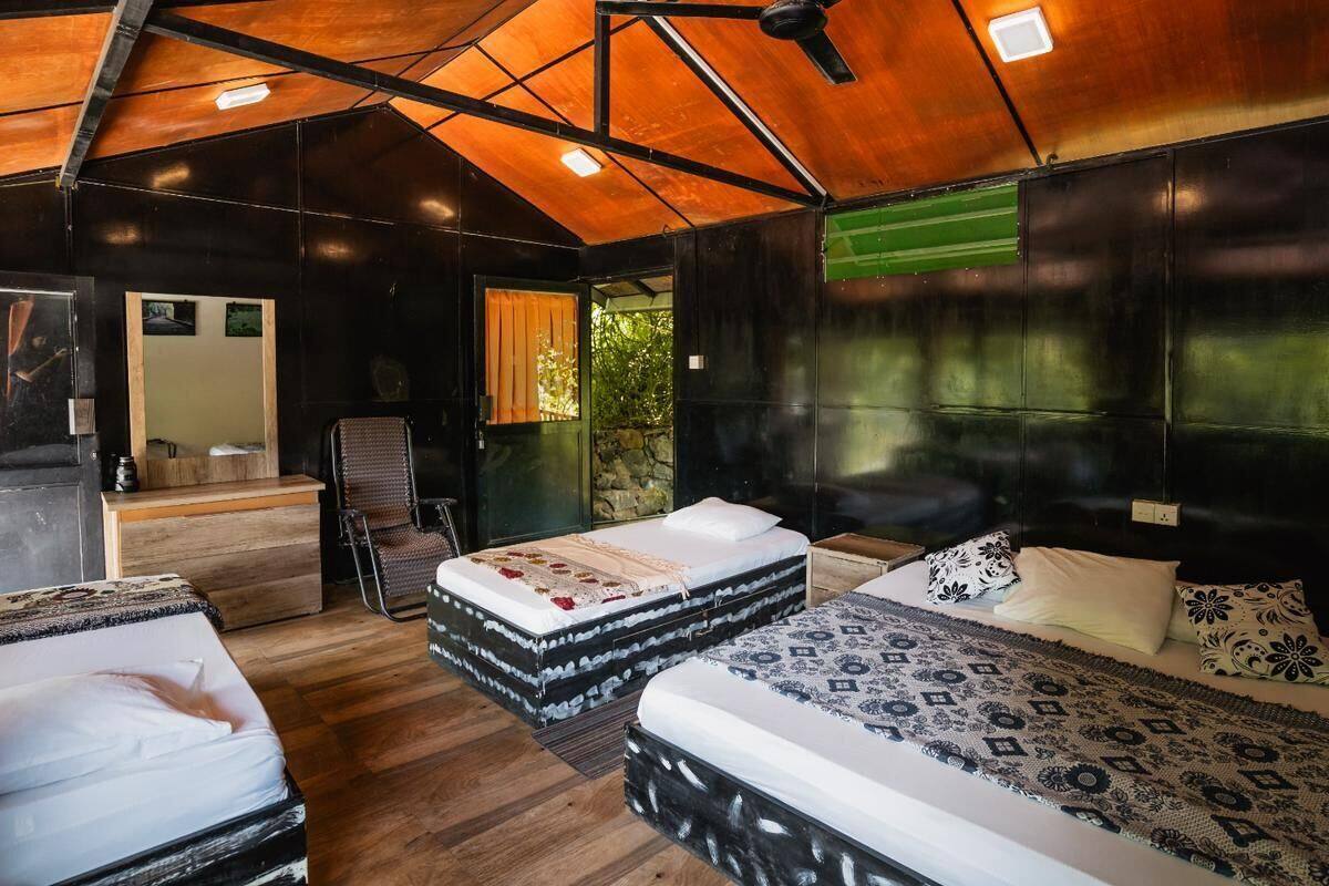 A cozy, rustic bedroom with two beds, a wooden ceiling, and a small seating area.