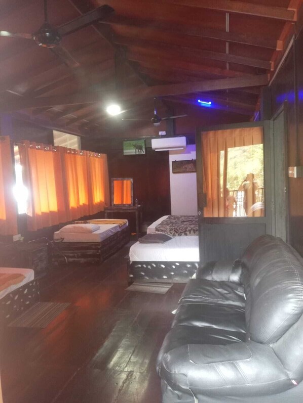 Une chambre avec deux lits, un canapé, un plancher en bois et un ventilateur de plafond.