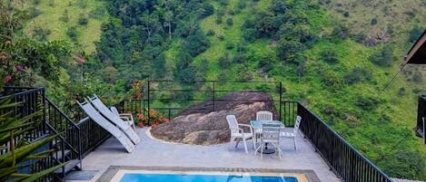 A swimming pool with a view of a lush green hillside.