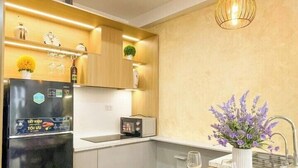 Une cuisine moderne avec un réfrigérateur noir, un four à micro-ondes et un petit îlot central agrémenté d’un verre à vin.