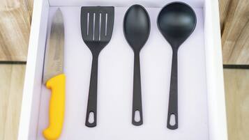 Un tiroir contenant un couteau, une spatule, une cuillère et un chiffre 1 jaune.
