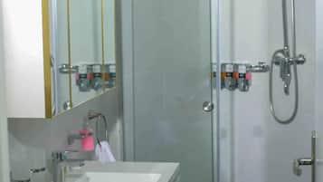 A modern bathroom with a glass-enclosed shower, a white sink, and a mirror with a gold frame.