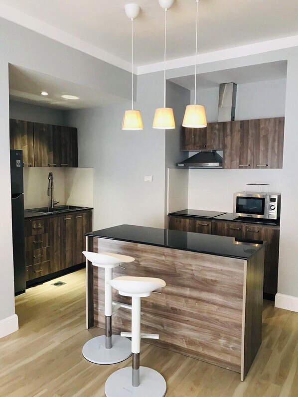 A modern kitchen with a central island, pendant lighting, and wooden cabinetry.