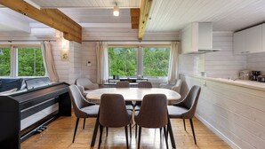 A modern kitchen with a dining area, wooden beams, large windows, and a piano. - Gekko Hanazono (Kutchan)