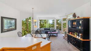 A spacious living area with a dining table, chairs, a sofa, and a large cabinet. - Snowcap Escape at Mount Bachelor w/ Pool & Hot Tub (Bend)