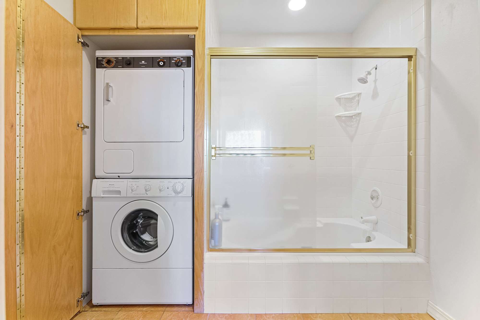 A laundry room with a washing machine and dryer, and a glass-enclosed shower area.