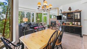 A spacious living area with a wooden dining table, black chairs, a sofa, and a fireplace. - Snowcap Escape at Mount Bachelor w/ Pool & Hot Tub (Bend)