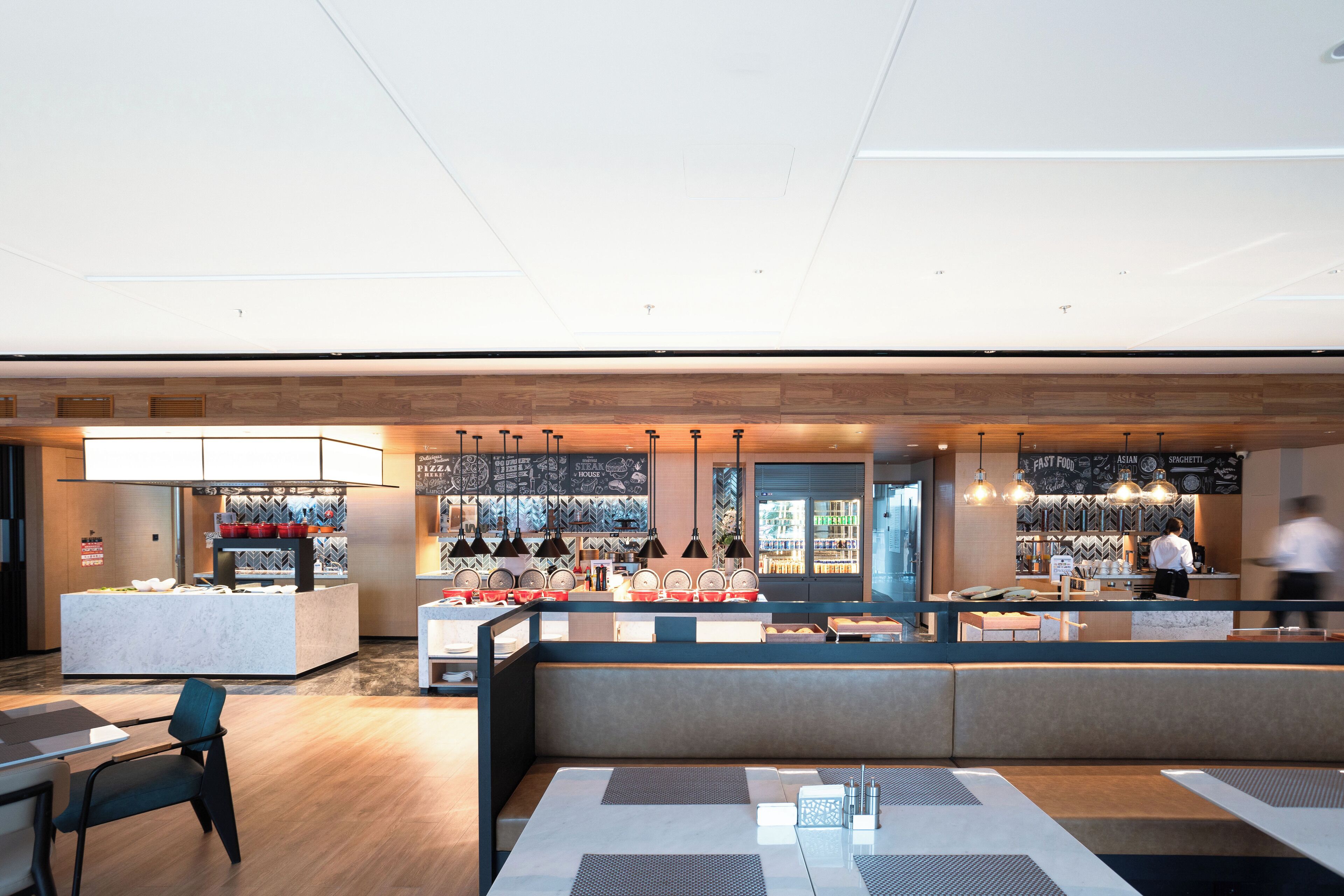 A modern restaurant with a central counter, seating areas, and a visible menu board.