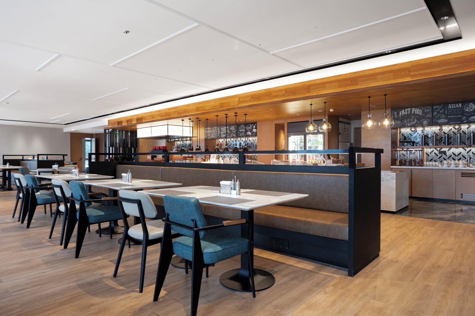 A modern restaurant with a long counter, booths, and a bar area.