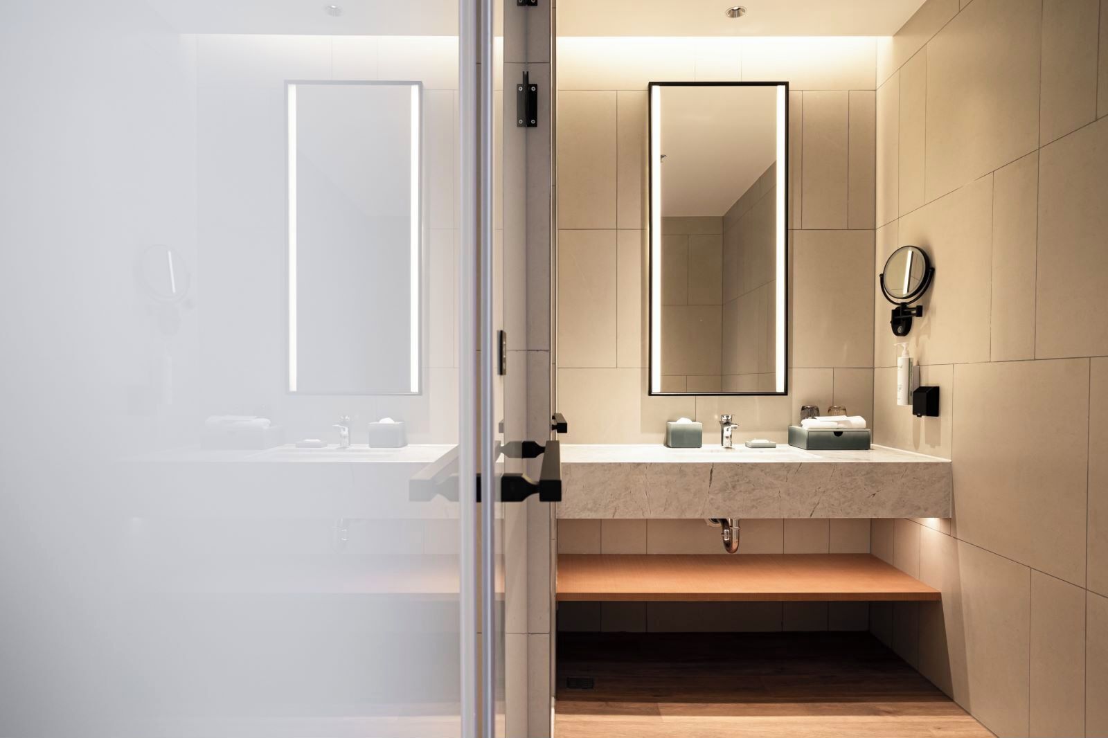 Un baño moderno con un espejo grande, un lavabo y un inodoro.