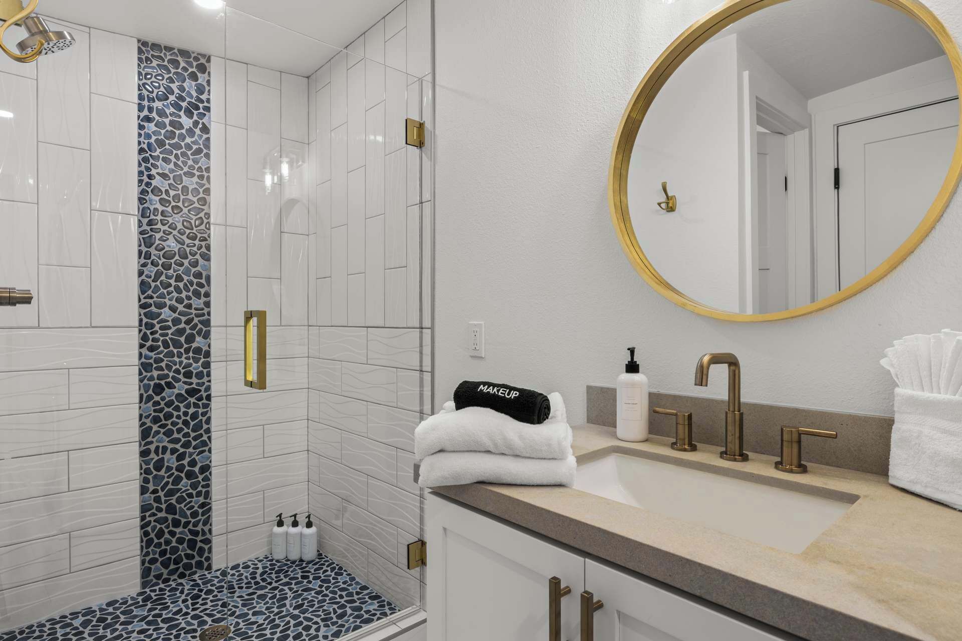 A modern bathroom with a shower, vanity, and a large mirror.