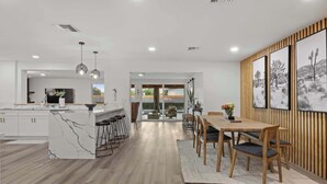 Een moderne keuken met een marmeren eiland, barstoelen en een eethoek met houten stoelen en een vloerkleed.