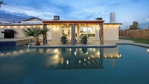 Een modern huis met een zwembad, terras en een zitgedeelte buiten.
