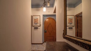 A hallway with a wooden door, a mirror, and framed artwork on the walls. - ROMA TRASTEVERE "SUITE BENEDETTA" (Roma)