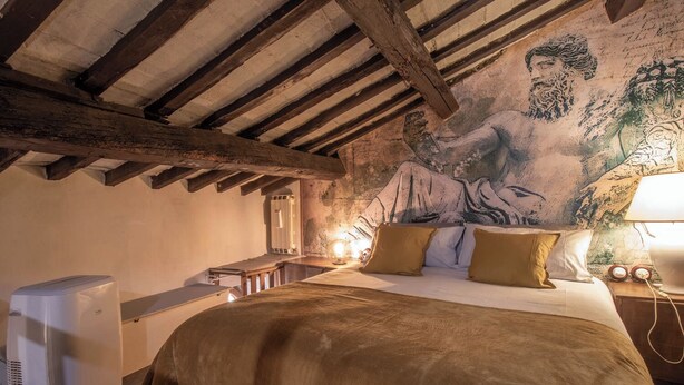 A rustic bedroom with a large bed, a wooden ceiling, and a mural on the wall. - ROMA TRASTEVERE "SUITE BENEDETTA" (Roma)