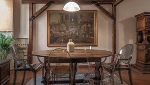 A dining area with a round wooden table, four chairs, a vase, and a large painting on the wall. - ROMA TRASTEVERE "SUITE BENEDETTA" (Roma)
