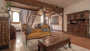 A spacious living room with a wooden sofa, a coffee table, and a large wooden cabinet. A staircase leads to an upper level, and a painting is visible on the wall. - ROMA TRASTEVERE "SUITE BENEDETTA" (Roma)