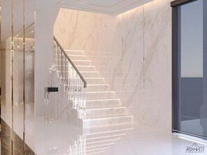 Una escalera moderna con un diseño elegante, paredes de mármol y una puerta de vidrio en la parte superior.