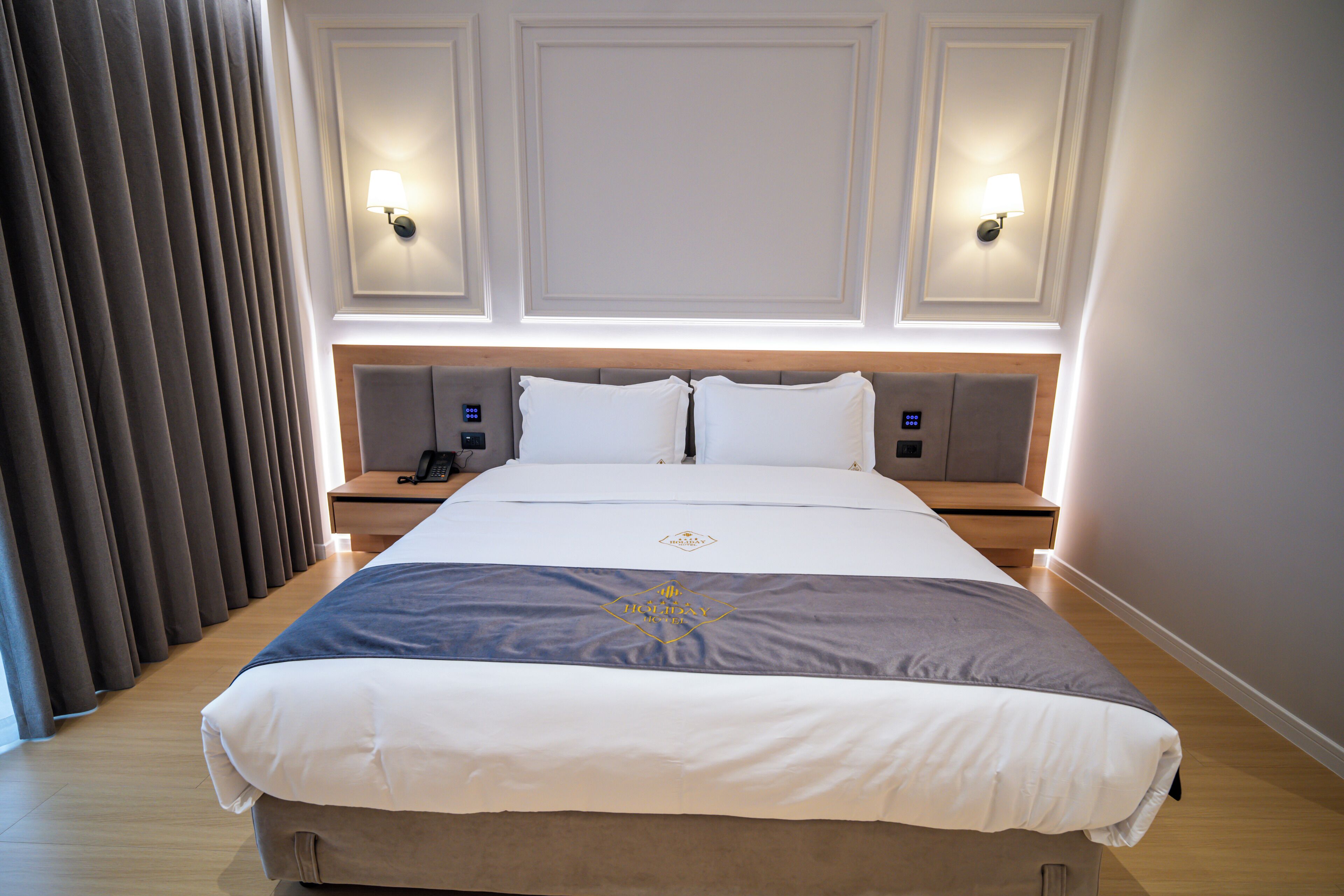 Habitación de hotel con una cama grande, dos mesitas de noche, una lámpara y una lámpara de pared.