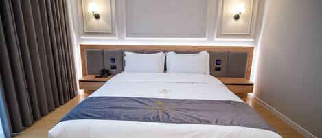 Habitación de hotel con una cama grande, dos mesitas de noche, una lámpara y una lámpara de pared.