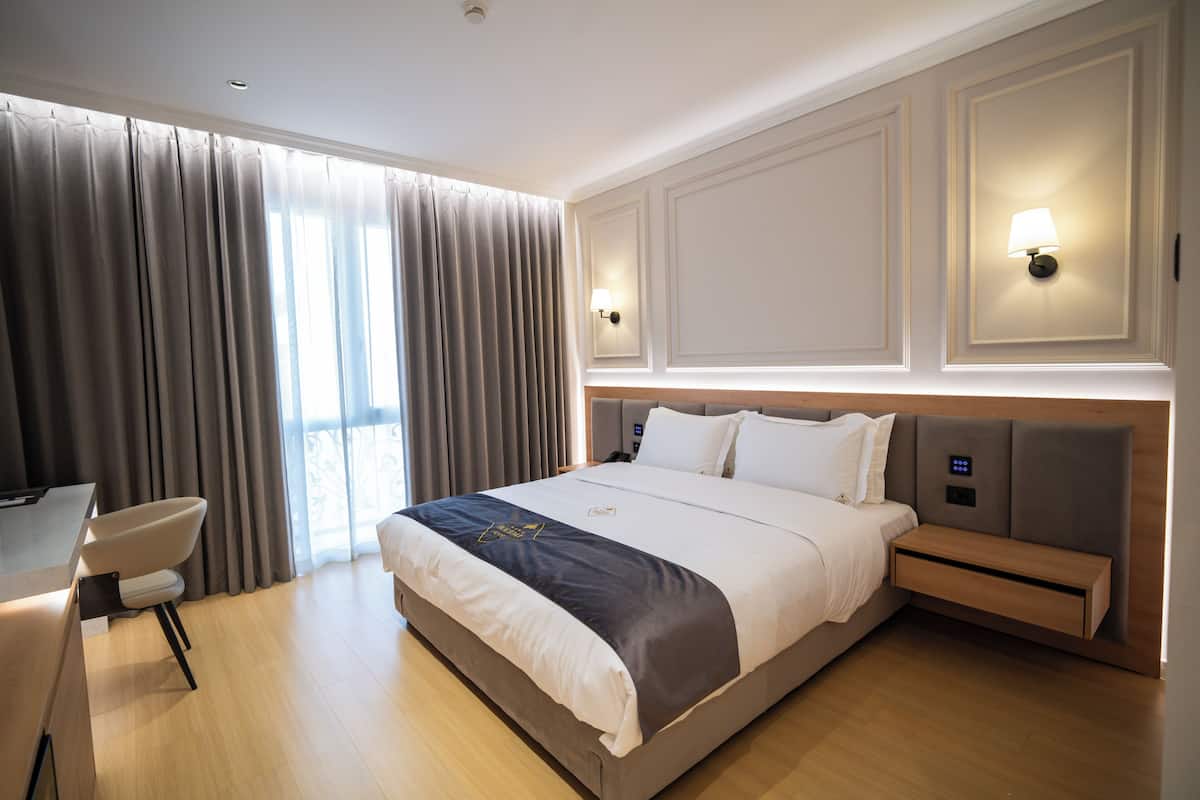 Une chambre d’hôtel moderne avec un grand lit, des tables de chevet, un bureau et une chaise.
