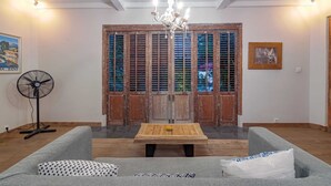 Un salon avec une table en bois, un canapé gris et un ventilateur.