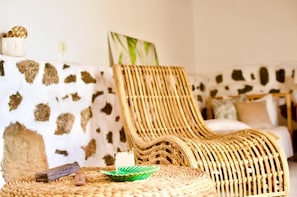 Una silla de mimbre en una habitación con pared estampada de piel de vaca y un tapete tejido en el suelo.