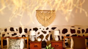 A room with a cowhide-patterned wall, a macrame wall hanging, two bedside tables with lamps, and a patterned pillow. - Studio With Pool, Garden and Open Roof Bathroom (La Oliva)