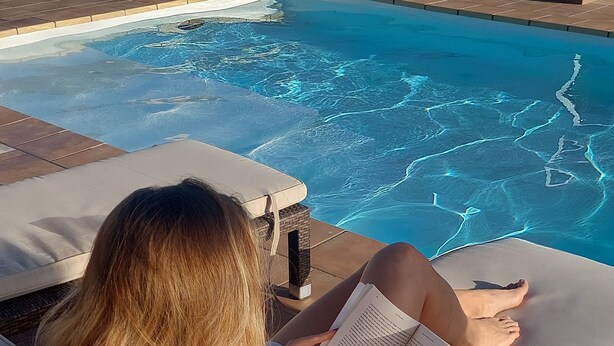 A person relaxing on a lounge chair by a pool with a book. - Studio With Pool, Garden and Open Roof Bathroom (La Oliva)