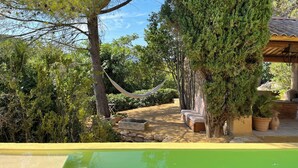 Un jardín con una hamaca, un sendero de piedra y un banco de madera.