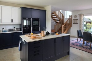 A modern kitchen with dark cabinets, a central island, and a dining area with a view.
