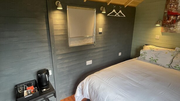 A room with a bed, a small table with a kettle, and a wall-mounted shelf. - Enchanted Cabin Retreat in Sibford Gower (Banbury)