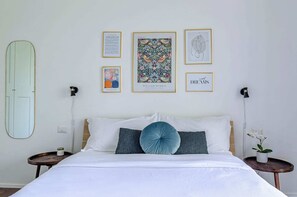 Una camera da letto ordinata con un letto, comodini, uno specchio e quadri appesi al muro.