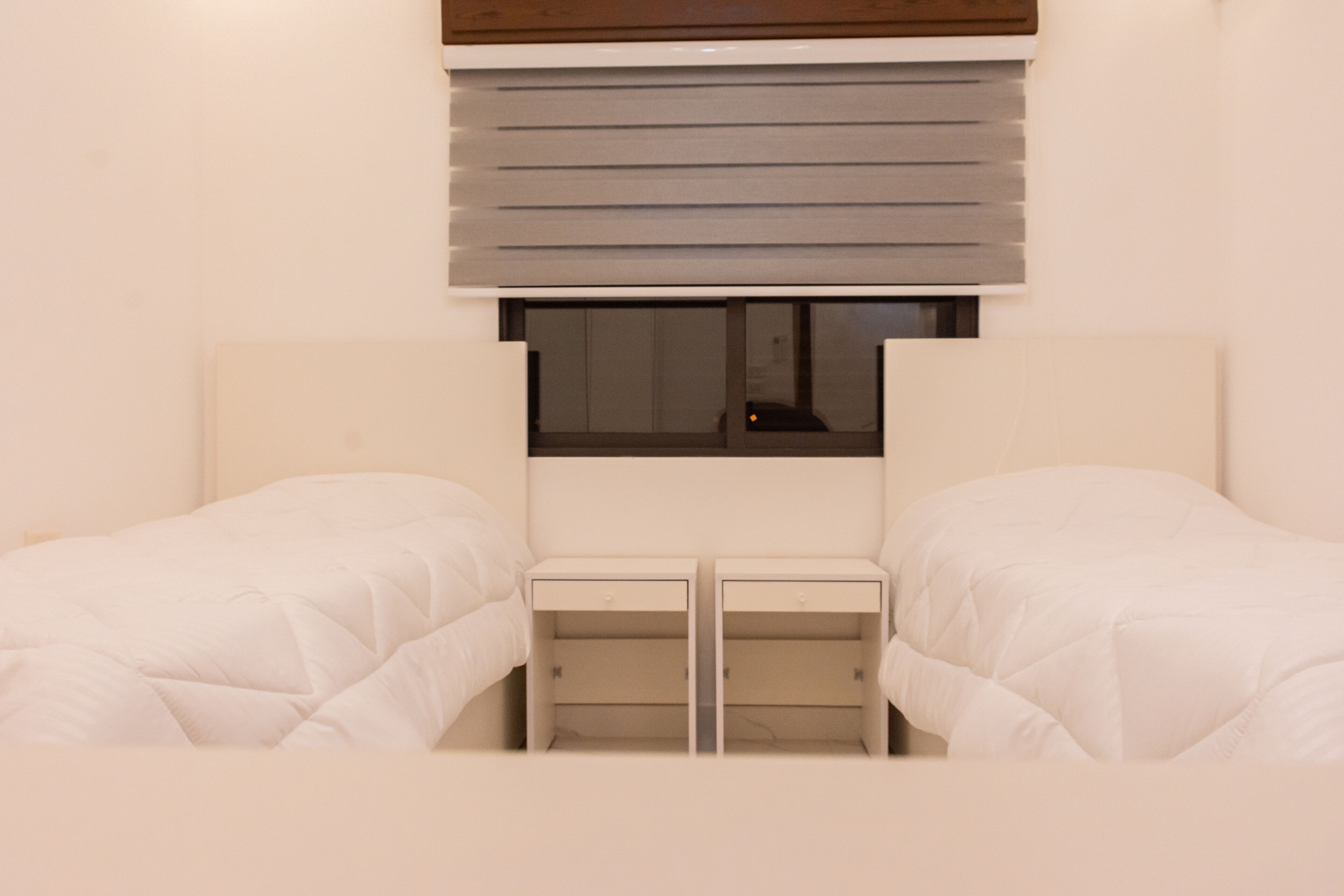 Une chambre avec deux lits, une fenêtre et une table de chevet.