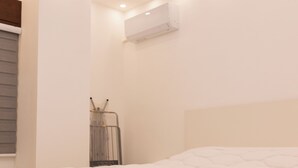 Un dormitorio con cama, luces empotradas en el techo, aire acondicionado y ventana con persianas.